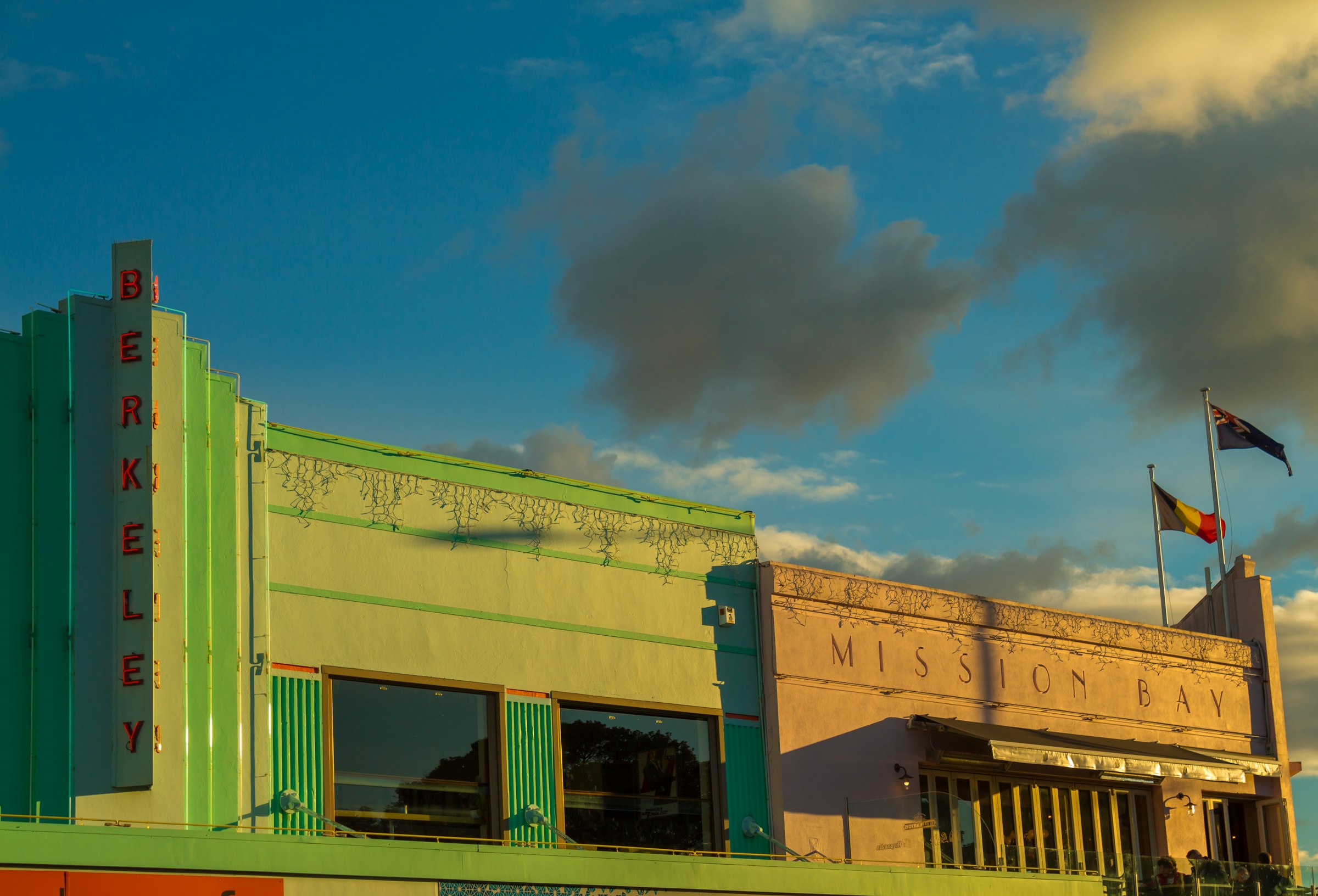 The art deco Berkeley cinema and the Mission Bay building on Tamaki Drive, under a late-afternoon sky.