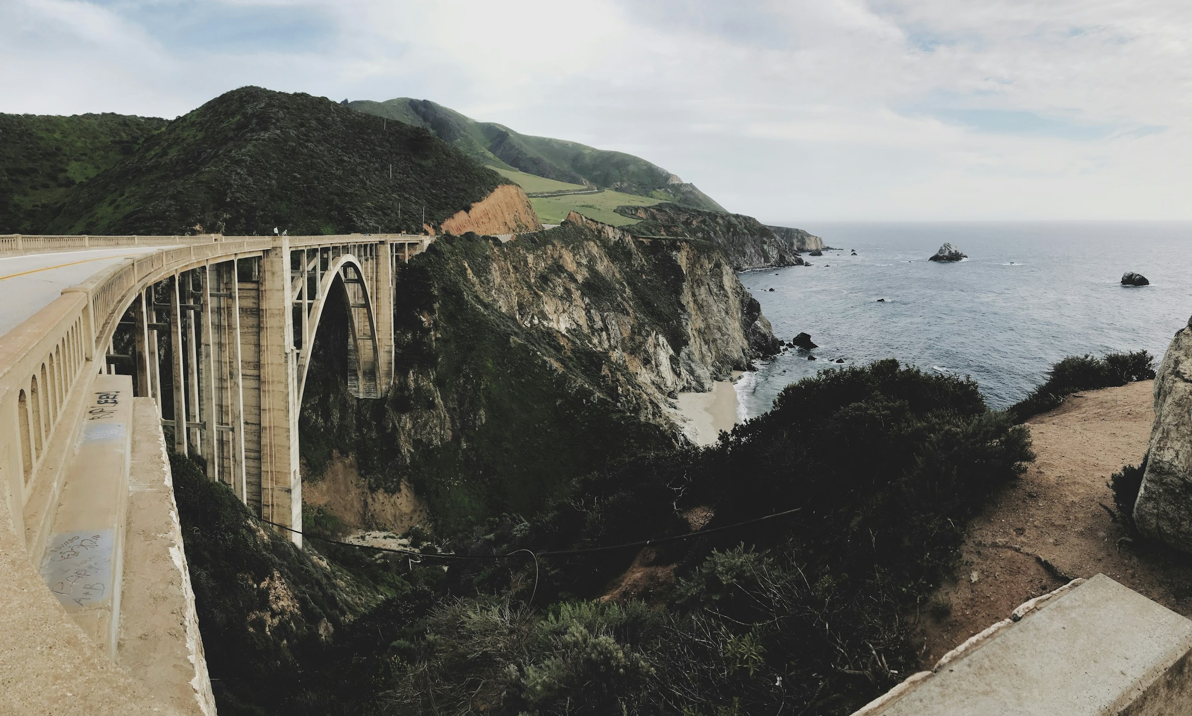 A white bridge on the Big Sur coast with the ocean stretching away beside it.