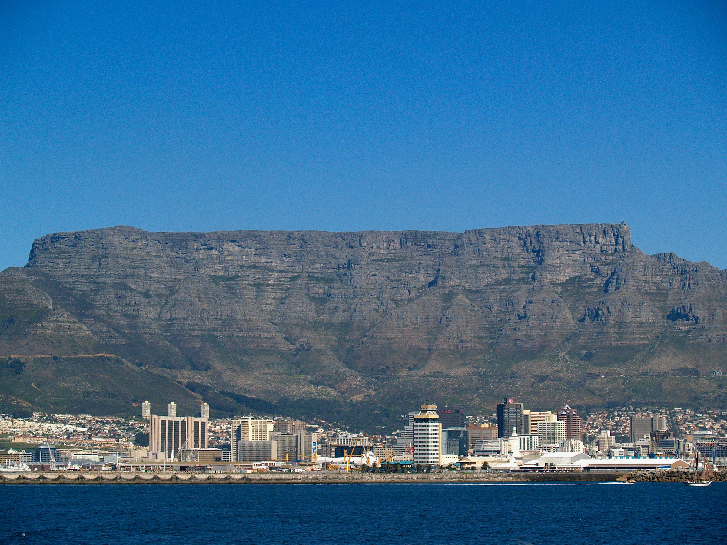 The flat top of Table Mountain above the Cape Town city centre, seen across the blue water of Table Bay.