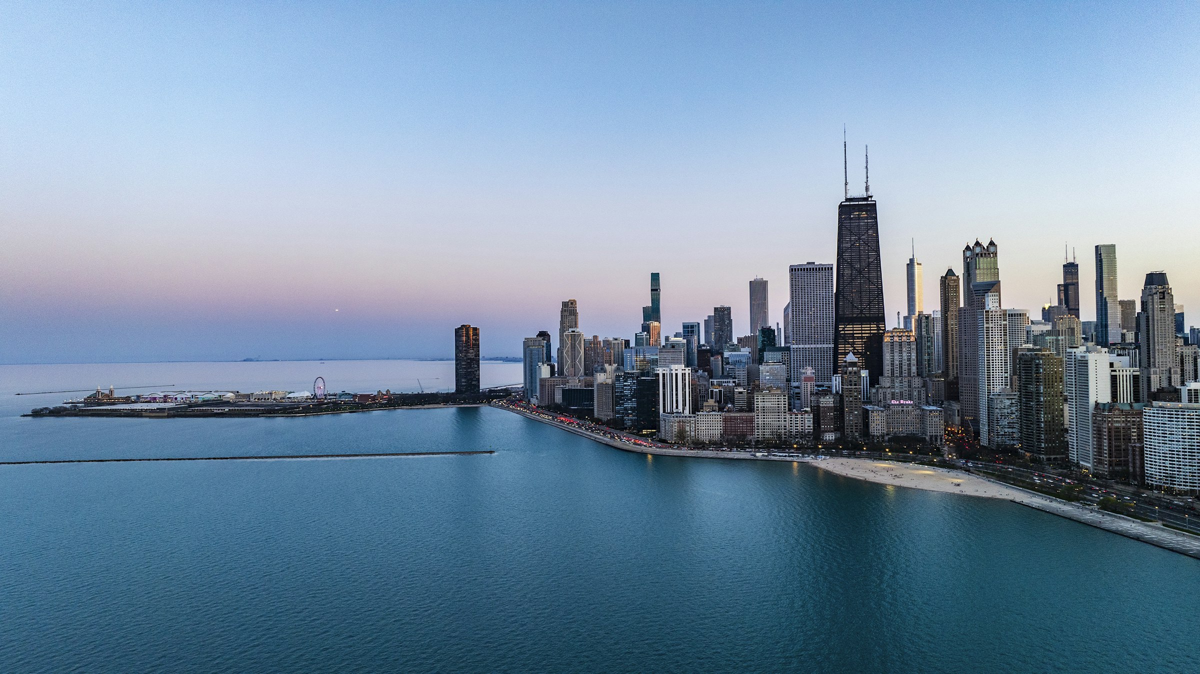 Chicago beside Lake Michigan from the air, the city flat to the horizon.