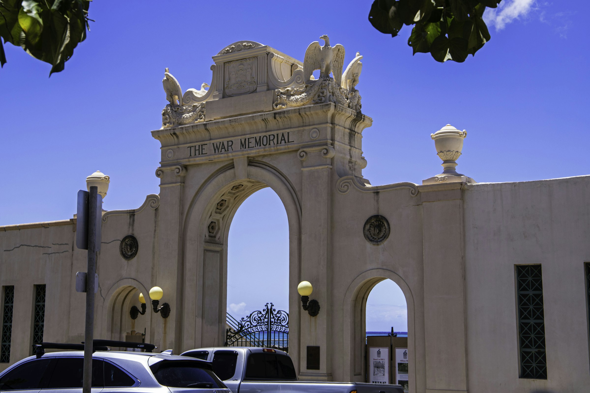 The ornate white arch of the Waikiki War Memorial Natatorium under a blue sky.