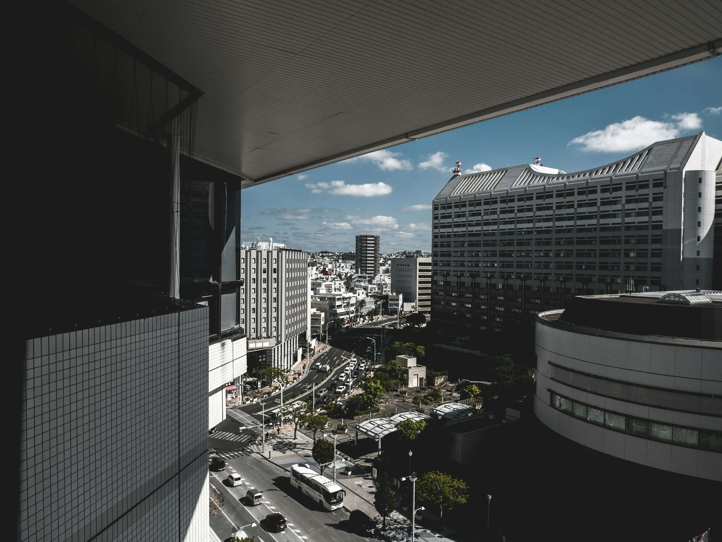 Central Naha from a high balcony, with office buildings and a road below.
