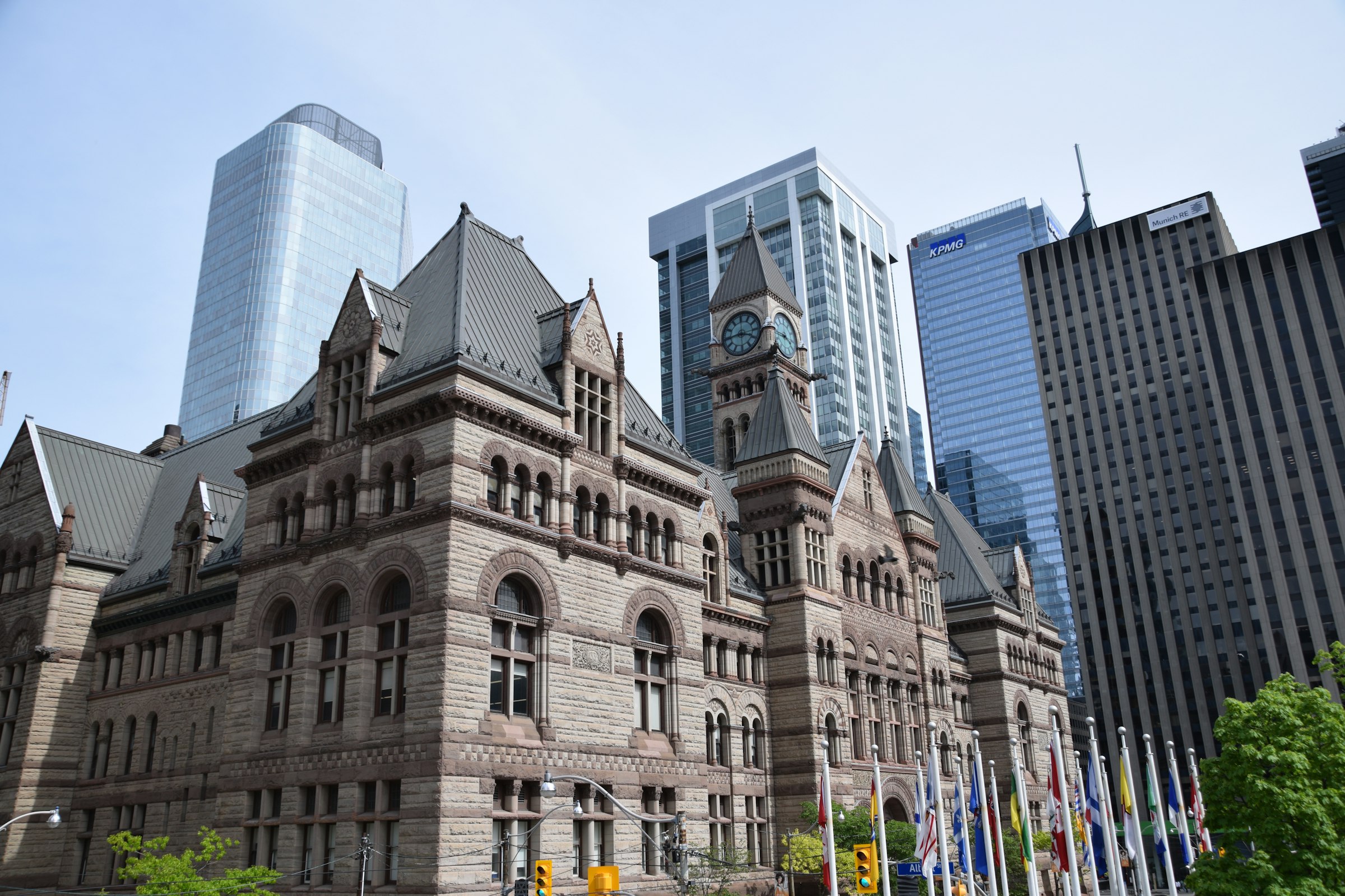 The Romanesque sandstone clock tower of Toronto's Old City Hall against glass office towers.