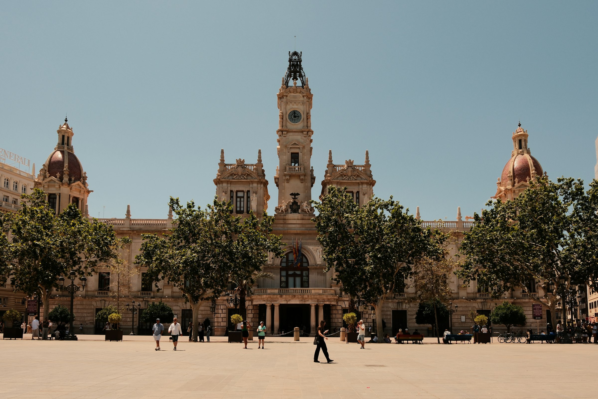 Valencia's city hall, a stone building with a central clock tower, across a wide paved square.