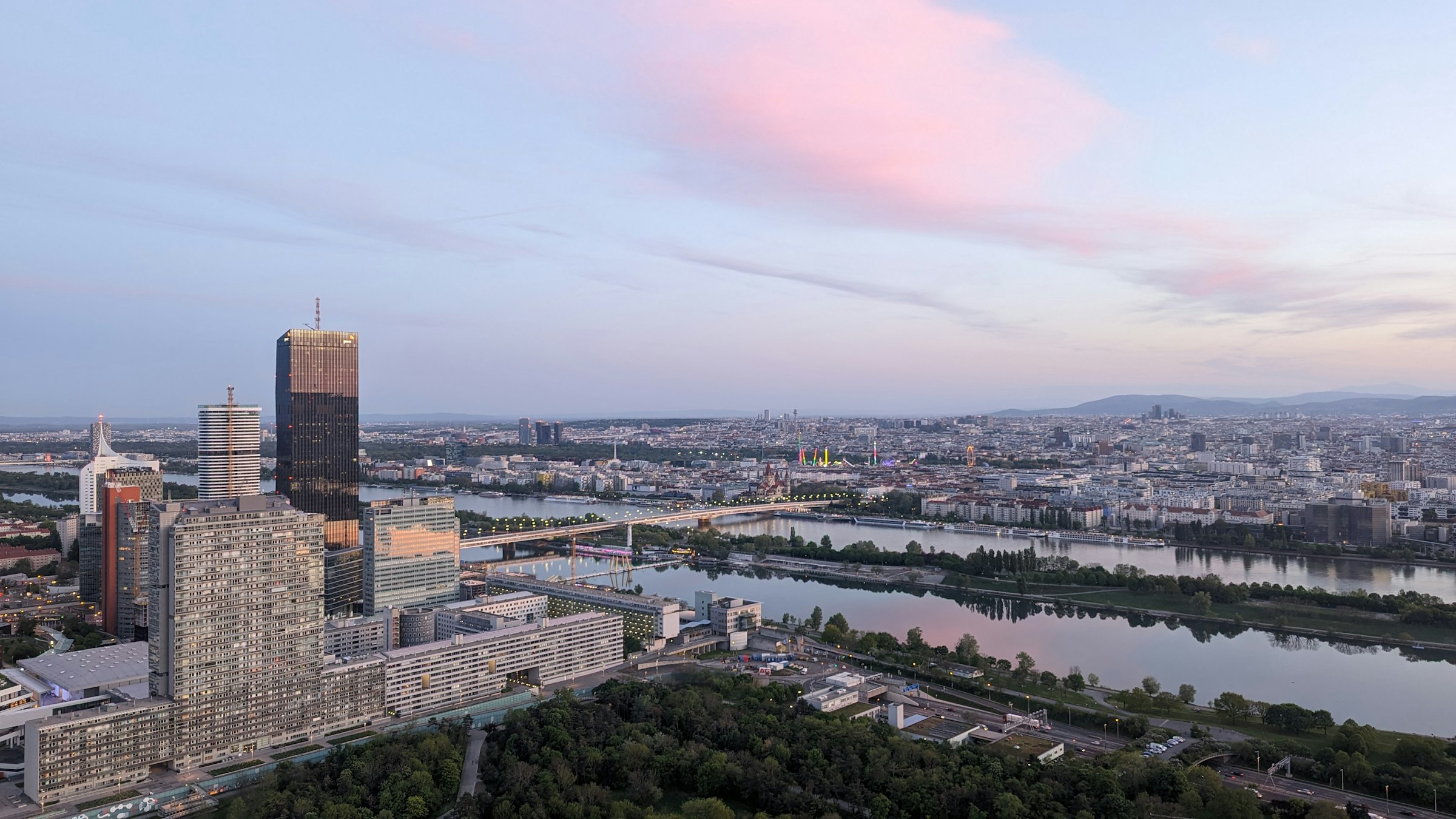 The Danube curving through Vienna at dusk, with a tall dark tower and apartment blocks on the near bank.